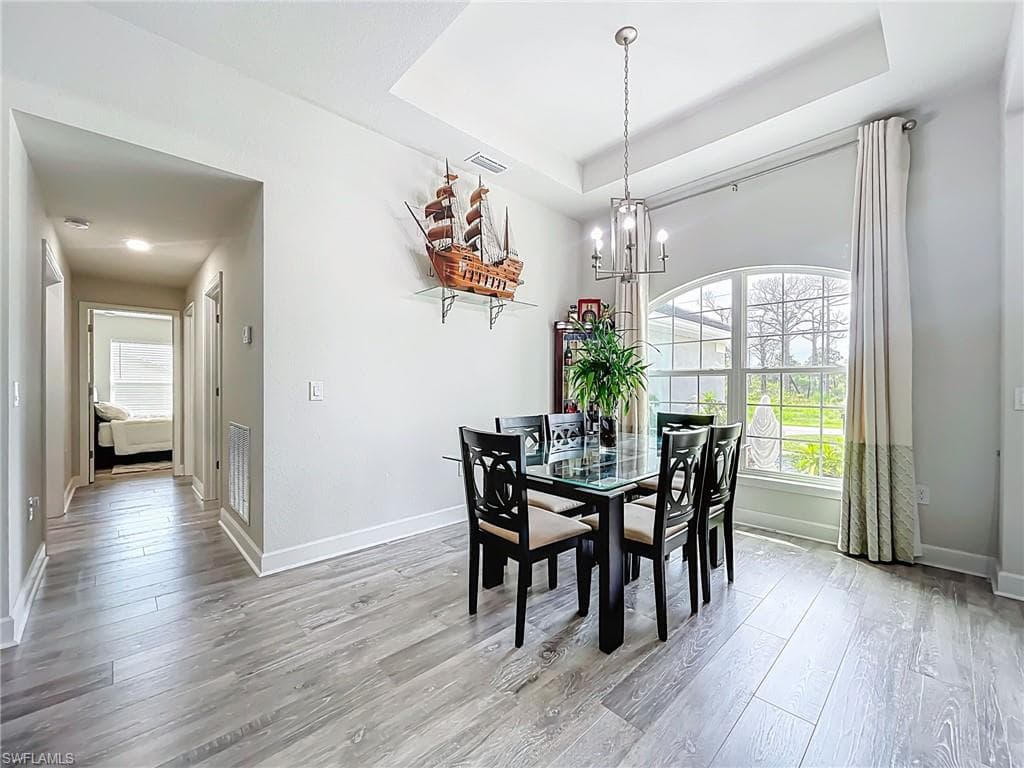Dining space featuring a chandelier, light wood-style flooring, and a tray ceiling
