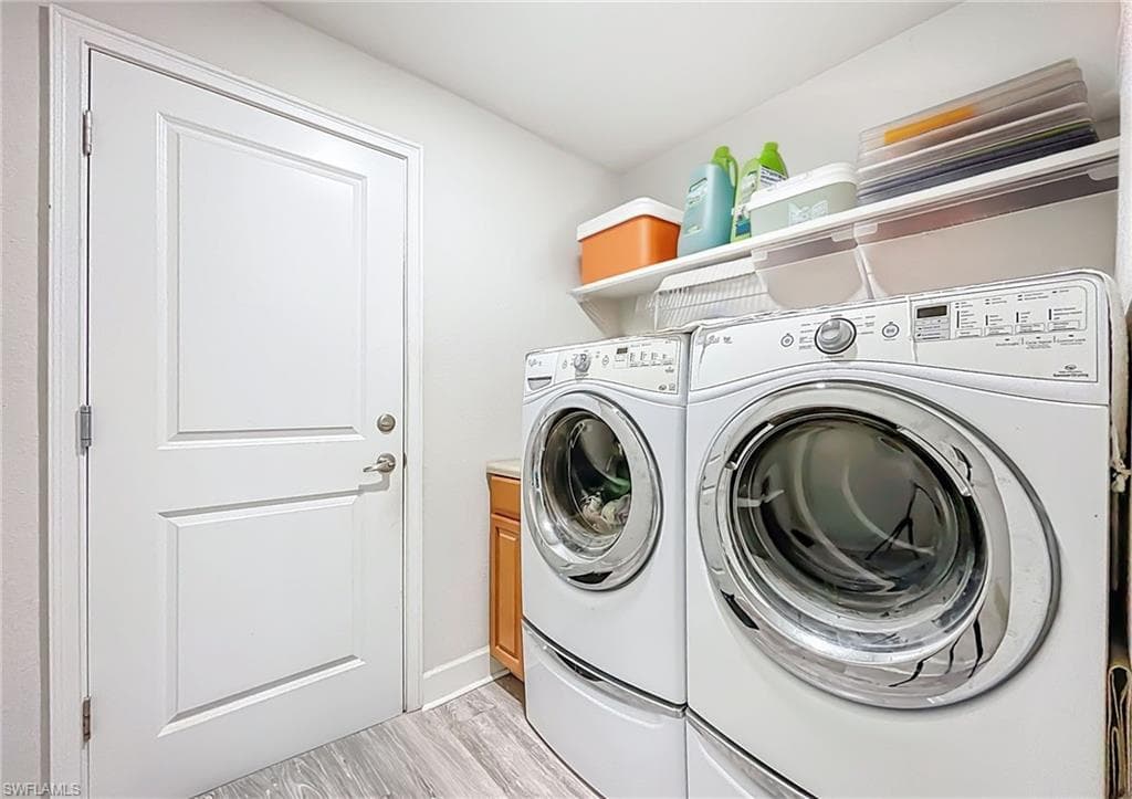 Laundry room featuring light wood-type flooring, separate washer and dryer, and cabinet space