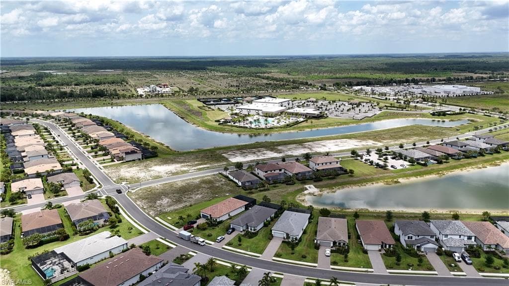 Expansive residential community featuring a network of streets, a variety of single-family homes, multiple water features, and a distant commercial complex