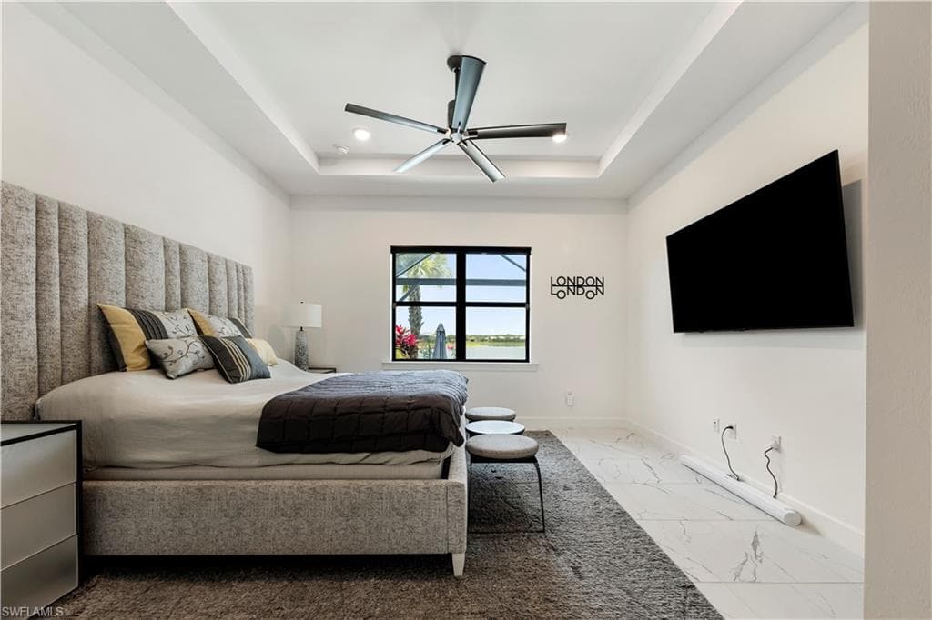 Bedroom featuring a tray ceiling with recessed lighting and a ceiling fan