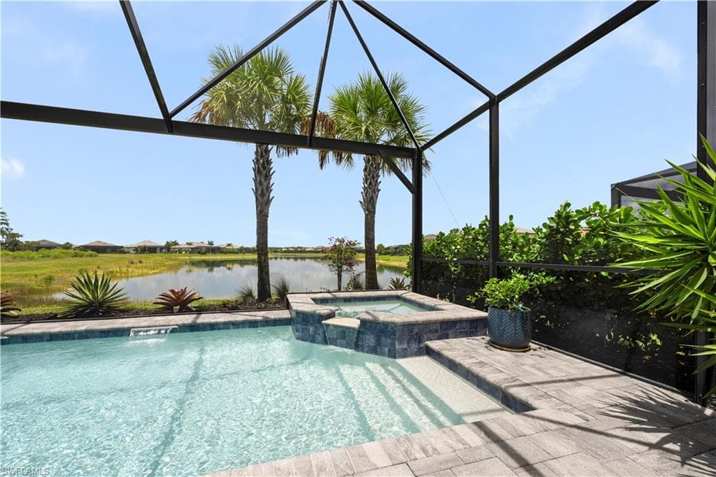 Screened-in outdoor living space featuring a swimming pool, integrated spa with tile surround, paver decking, and mature landscaping