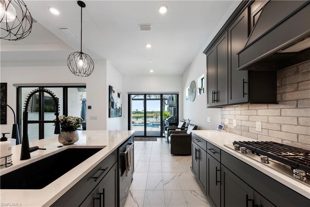 Modern kitchen featuring dark cabinetry, light countertops, and a subway tile backsplash