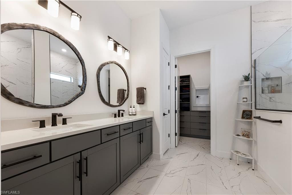 Dual vanity with dark gray cabinetry, matte black fixtures, and organic-shaped mirrors