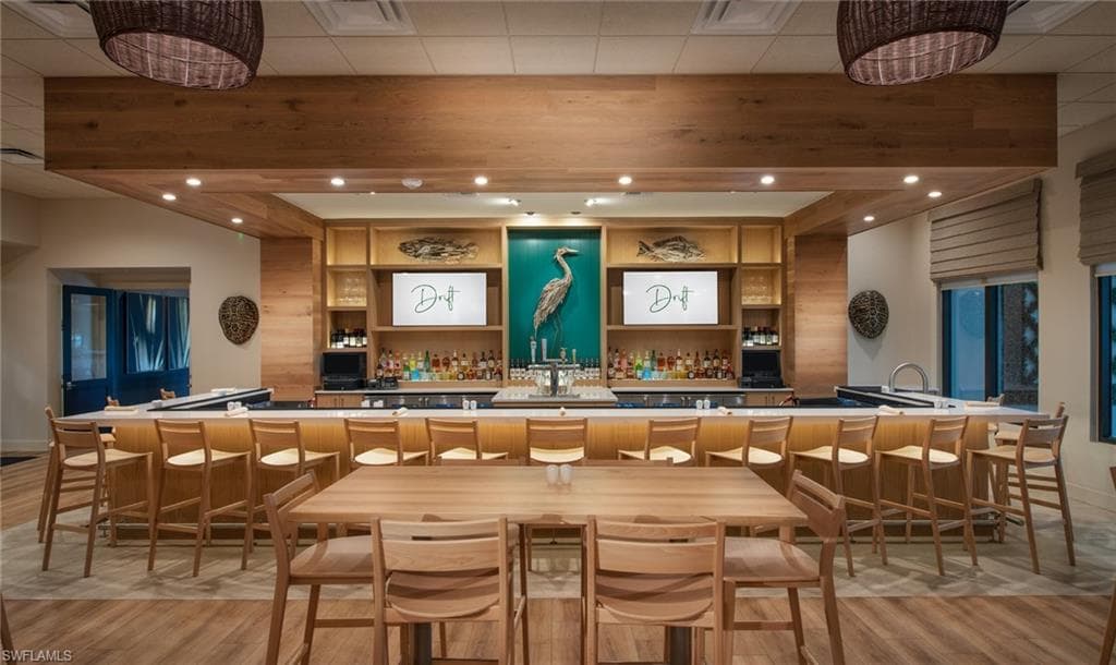 Expansive bar area featuring a wood-finish bar top with integrated sinks, under-counter lighting, and a selection of bar stools