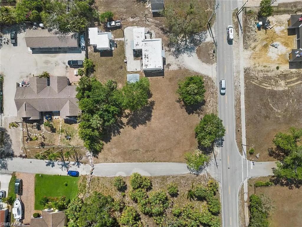 Expansive land parcel with direct road frontage, featuring mature trees and a clear, level building area