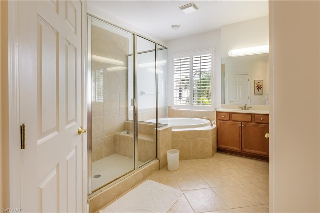 Bathroom with tile patterned floors, independent shower and bath, and vanity