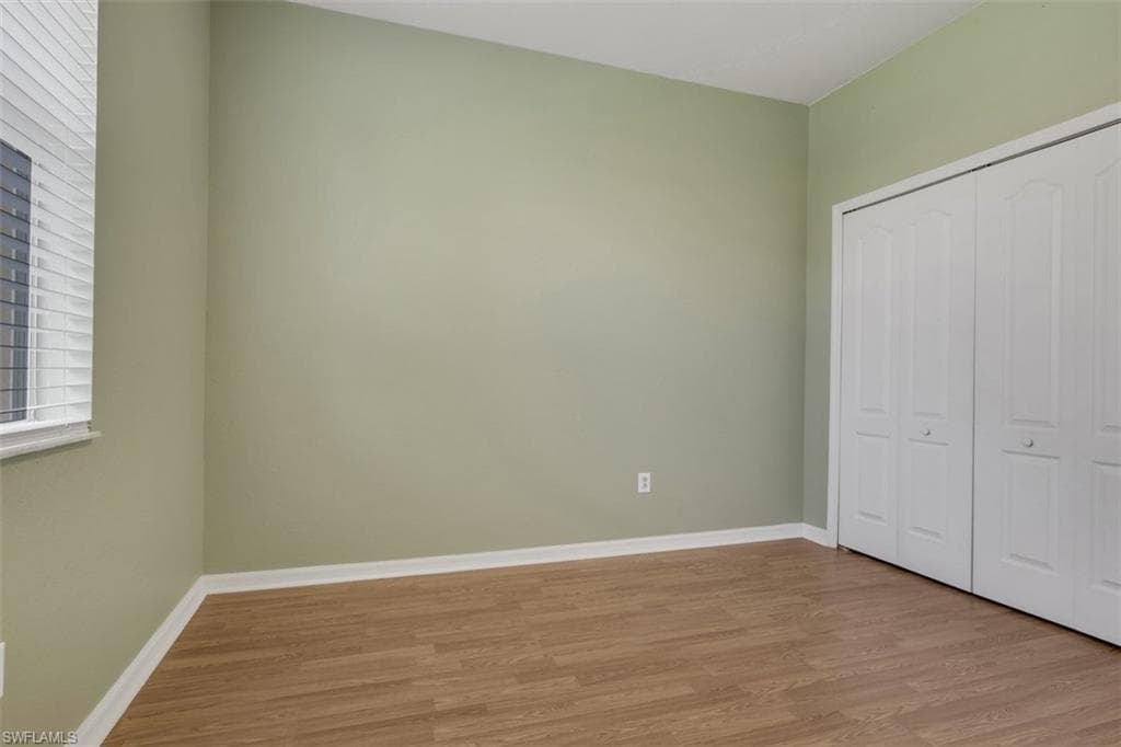 Unfurnished bedroom with wood finished floors and a closet