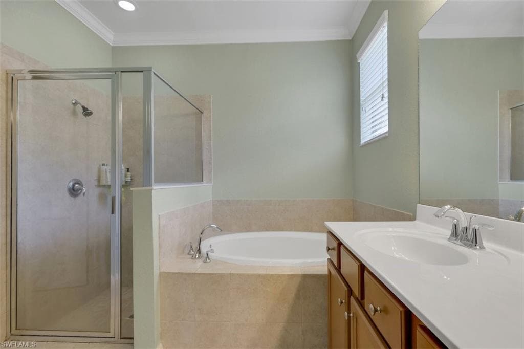 Bathroom featuring vanity, a garden tub, a stall shower, and crown molding