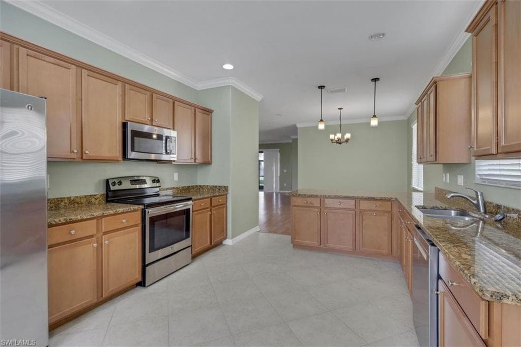 Kitchen with dark stone countertops, stainless steel appliances, a peninsula, crown molding, and suspended lighting