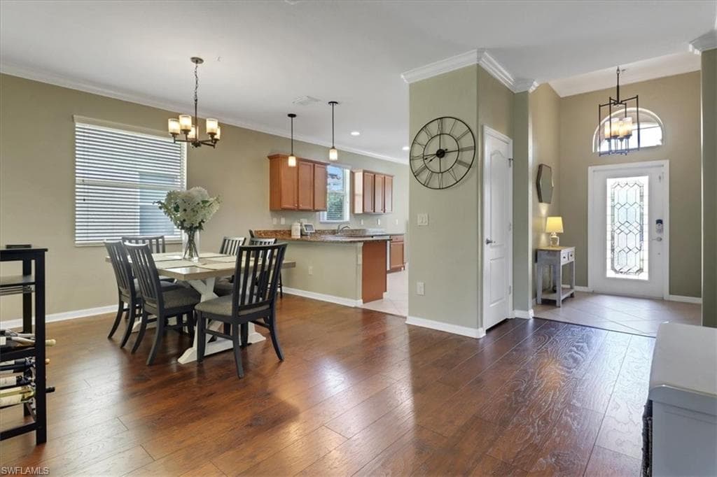 Dining room with an inviting chandelier, a healthy amount of sunlight, and ornamental molding