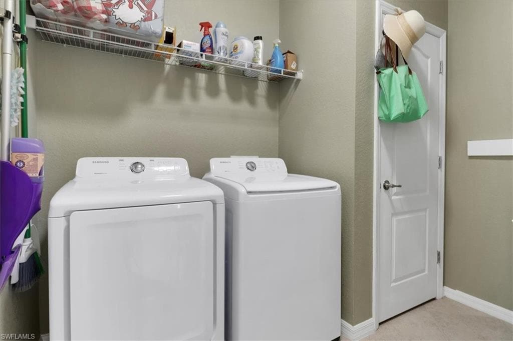 Clothes washing area with washer and clothes dryer, baseboards, and laundry area
