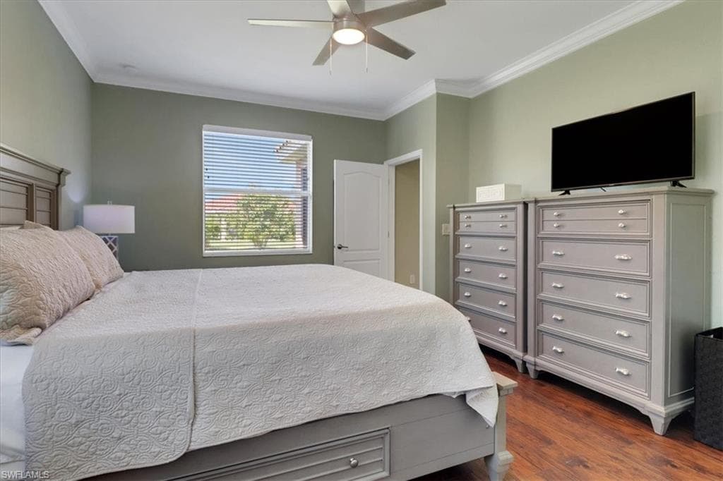 Bedroom featuring ornamental molding, dark wood-style floors, and ceiling fan