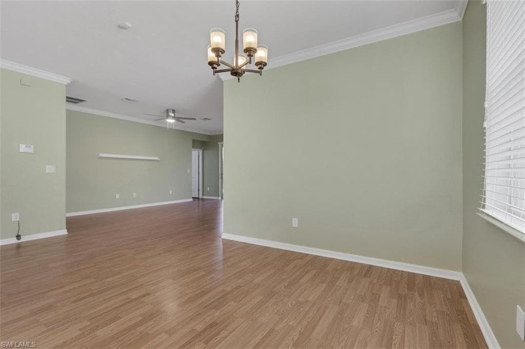 Spare room with crown molding, hanging lights, light wood-style floors, and ceiling fan