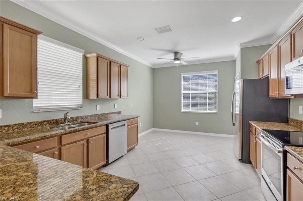 Kitchen featuring stainless steel appliances, dark stone countertops, ornamental molding, a ceiling fan, and recessed lighting