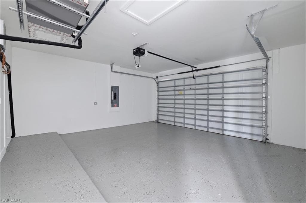 Garage interior featuring a light gray speckled epoxy floor, white painted walls, and a white ceiling