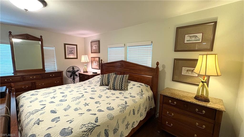 Primary Bedroom features wood-finish flooring, two large windows with blinds, snd ceiling light fixture.
