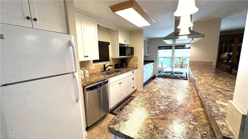 Kitchen featuring white cabinetry, ample countertops, newer appliances, tile flooring, and adjacent dining area.
