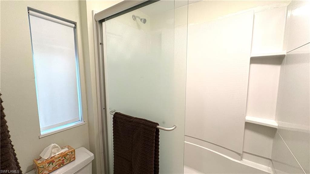 Primary bathroom has a shower-tub combination featuring a frosted glass enclosure and integrated shelving