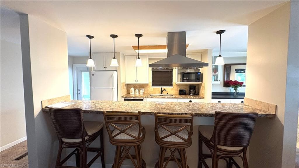 Spacious breakfast bar has a granite-finish countertop and pendant lights.