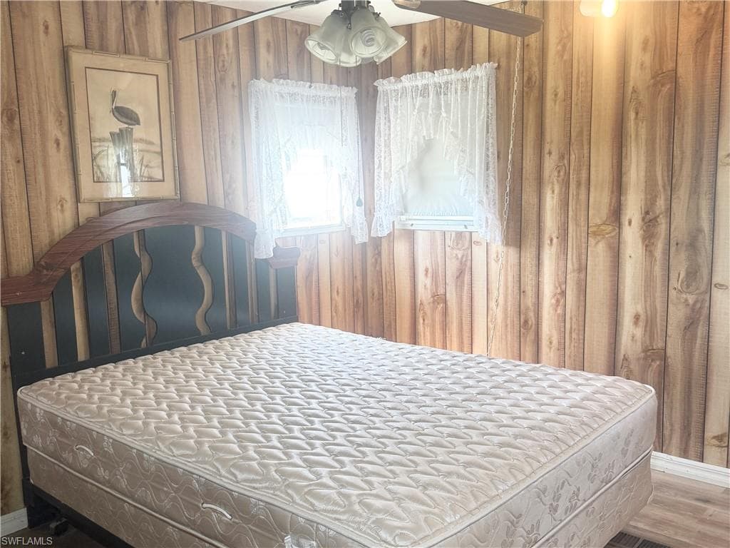 Wood-paneled room with two windows featuring lace valances