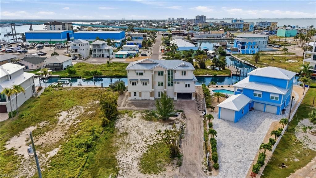 Waterfront property featuring a three-story residence with a multi-car garage, a paver driveway, and an outdoor swimming pool - Virtually Edited Image