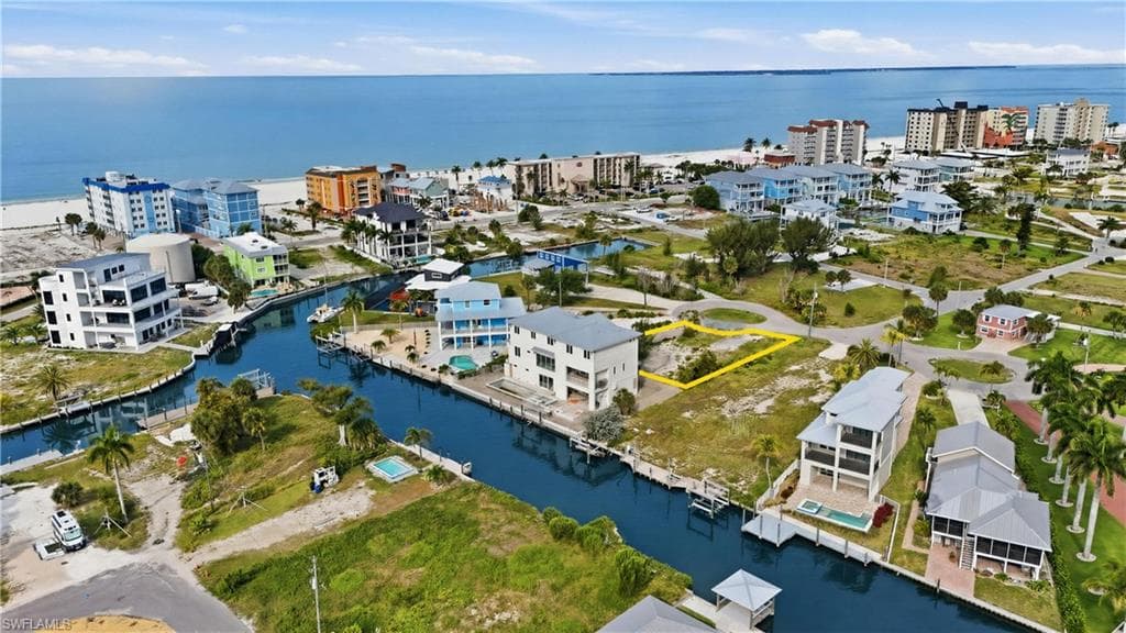 Canal-front lot with direct Gulf access, featuring a level buildable area, surrounding residential properties, and proximity to the open water and sandy beach - Virtually Edited Image
