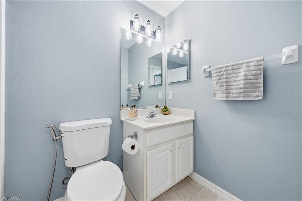 Bathroom featuring a white vanity with an integrated sink, a wall-mounted mirror, and vanity lighting