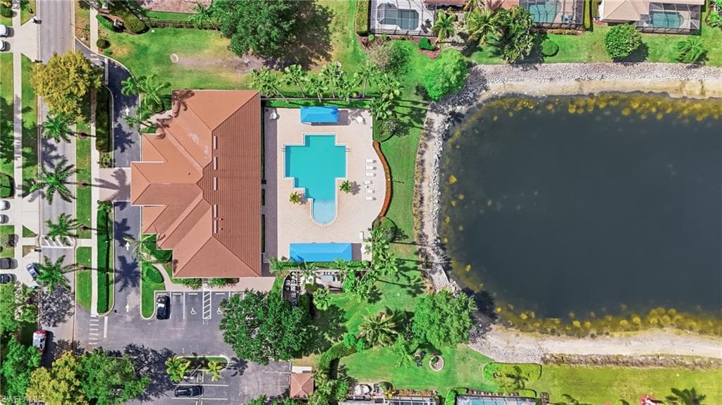 Clubhouse building with a multi-gabled roofline, adjacent to a resort-style swimming pool, a separate wading pool, and a paved sundeck