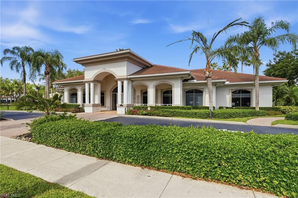 Stucco exterior with an arched portico, column accents, and a tile roof