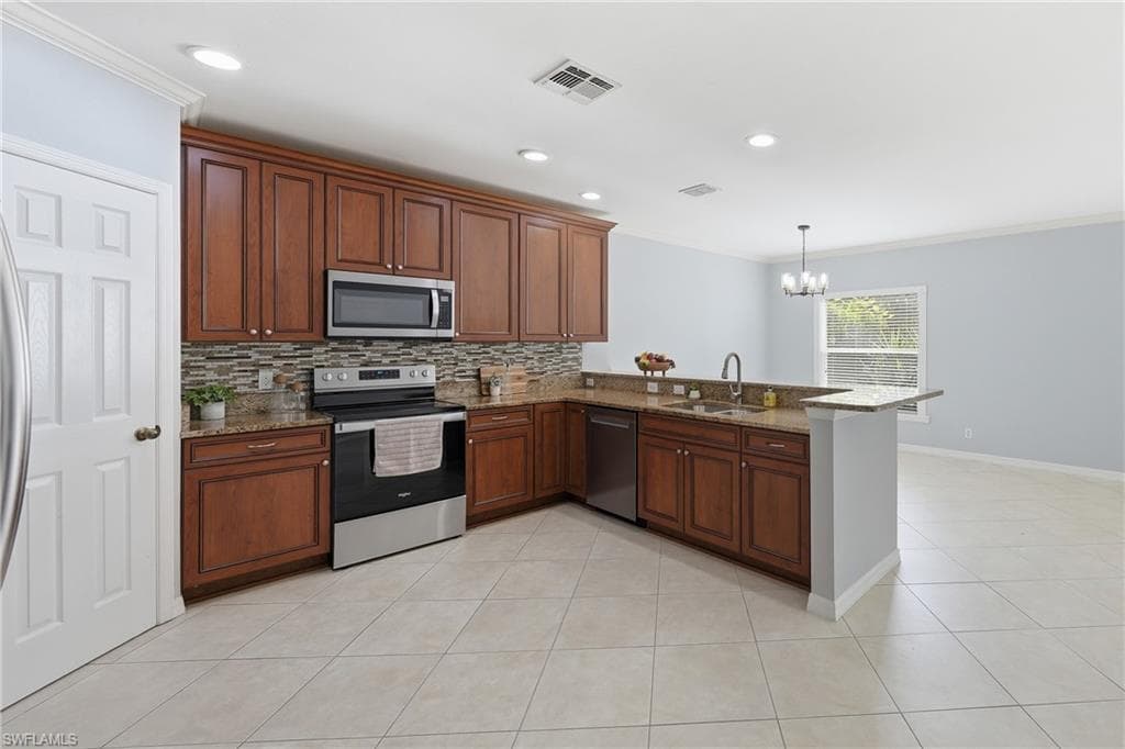 Kitchen featuring wood cabinetry, stainless steel appliances, granite countertops, and a mosaic tile backsplash