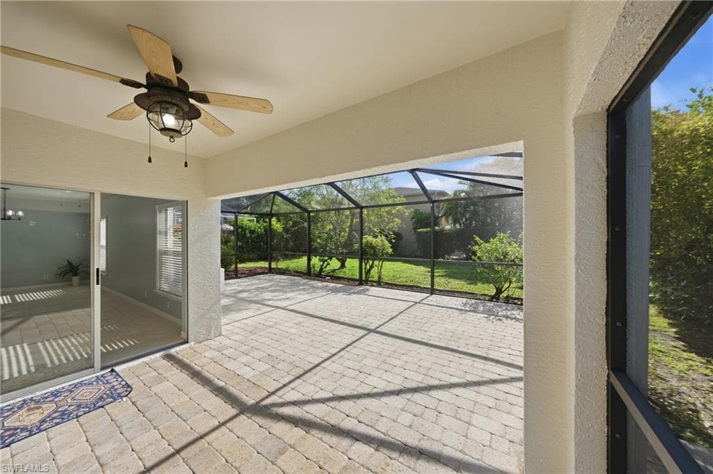 Expansive screened lanai featuring durable paver flooring and an outdoor ceiling fan