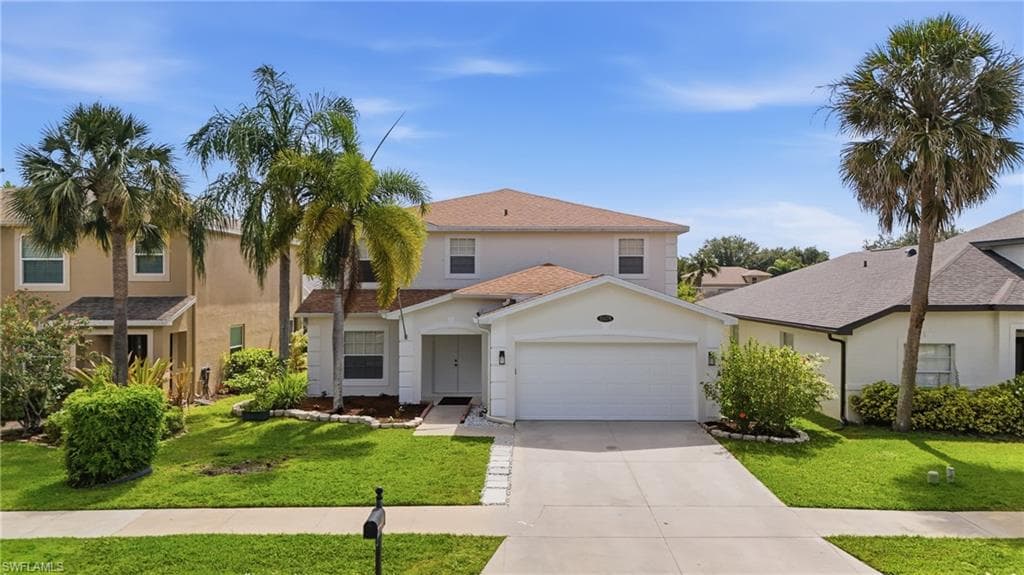 Two-story residence featuring a white stucco exterior, an attached garage, and a concrete driveway