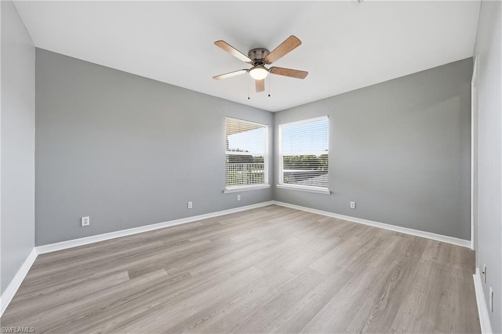 Spacious room featuring wood-finish flooring, light grey walls, and white baseboards