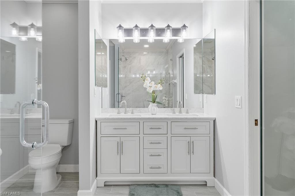 Dual vanity with white cabinetry and integrated sinks, complemented by a large mirror and multi-bulb fixture