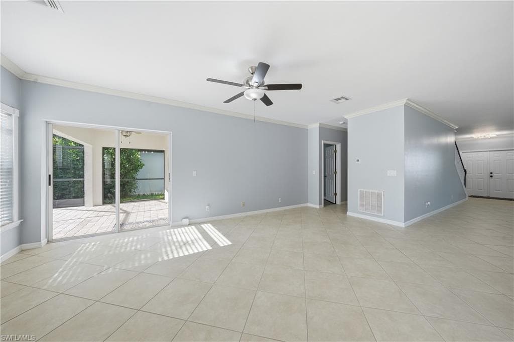 Spacious interior featuring neutral tile flooring, light blue wall paint, and white crown molding