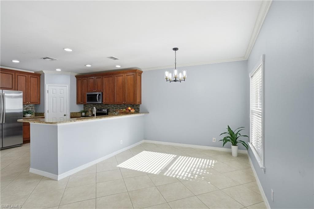Open-concept kitchen and dining area featuring warm wood cabinetry, stainless steel appliances, a granite-finish countertop, and a tiled backsplash