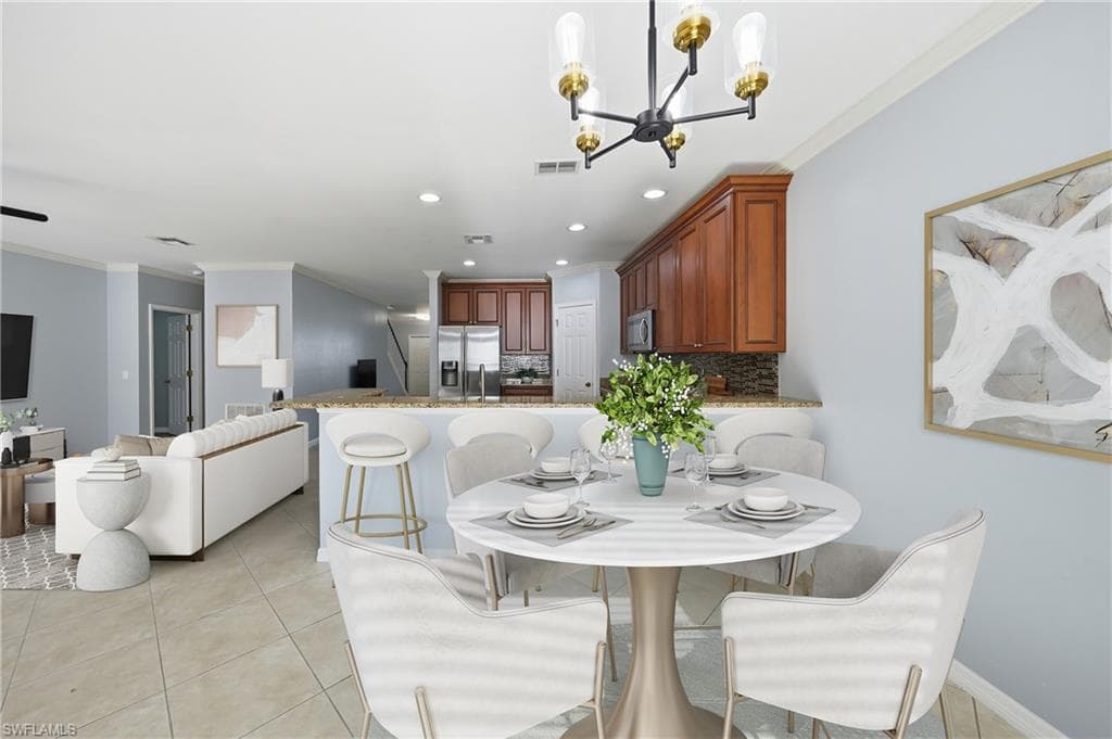Open-concept living area featuring tile flooring, a kitchen with wood cabinetry and a peninsula, and a dining area with a contemporary chandelier