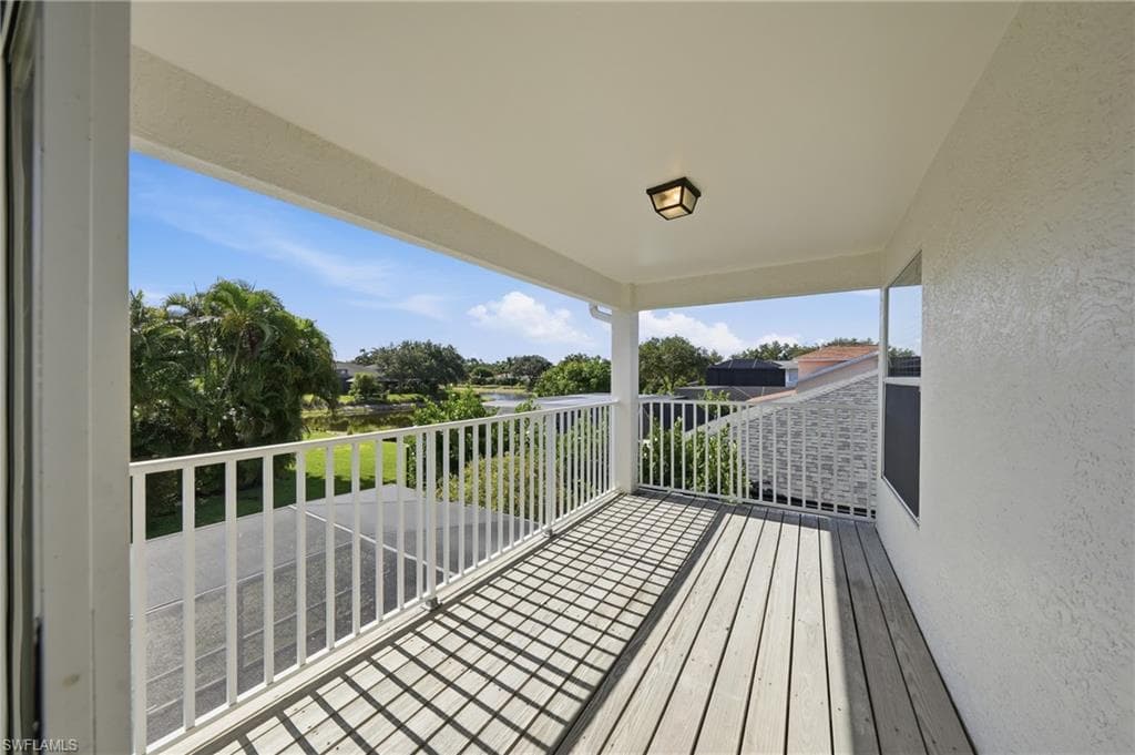 Covered balcony featuring wood-finish flooring, white railing, and a ceiling-mounted light fixture