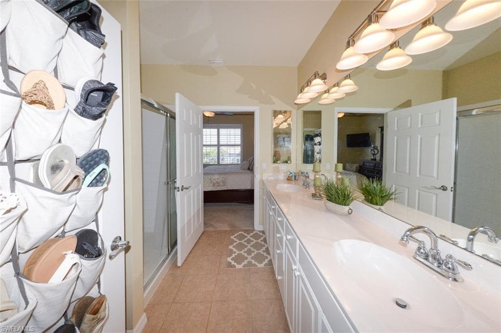 Primary suite bathroom with double sink vanity, upgraded lighting, Walk-in shower, tiled floor and large walk-in closet.