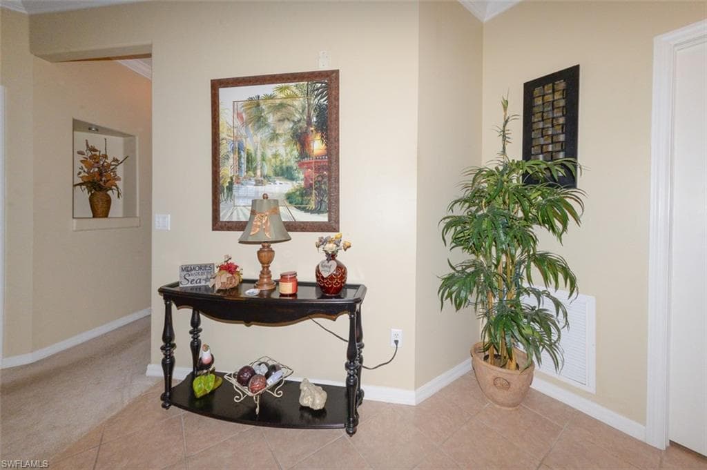 Tiled Entry Foyer with 9'4" ceilings & crown molding shows door on right to laundry room and hallway on left leading to Primary Suite.