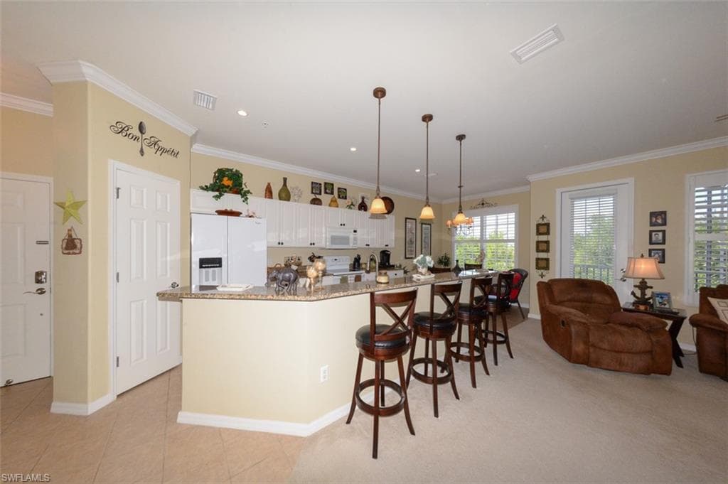 Open Kitchen features tiled flooring, a Breakfast bar, pantry, 9'4" ceilings, Crown molding, recessed and pendant lighting, White cabinetry, beautiful Granite Countertops, Plantation shutters and Dining area.