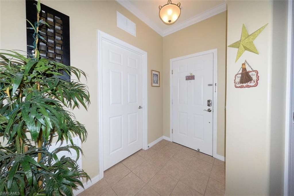 Tiled Entry Foyer with 9'4" ceilings & crown molding shows door on left to laundry room.