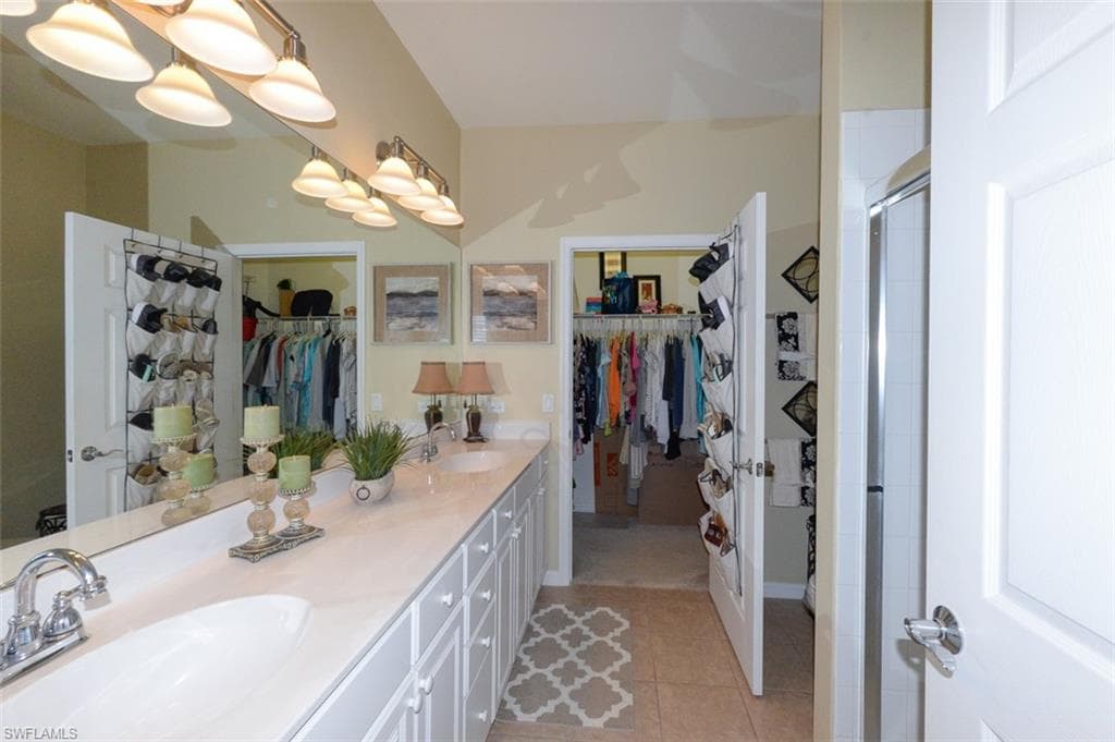 Primary suite bathroom with double sink vanity, upgraded lighting, Walk-in shower, tiled floor and large walk-in closet.