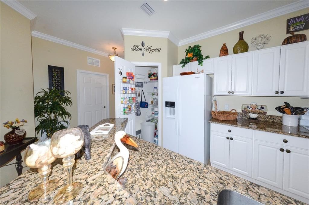 Open Kitchen features tiled flooring, a Breakfast bar, pantry, 9'4" ceilings, Crown molding, recessed and pendant lighting, White cabinetry, beautiful Granite Countertops, Plantation shutters and Dining area to right.