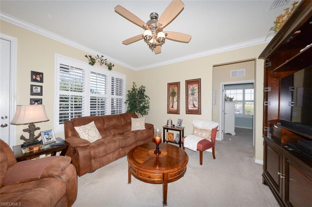 Spacious Great Room features 9'4" ceilings, Crown Molding, Plantation shutters, French door to Lanai and open to the Breakfast bar and Kitchen. Shows hallway leading to 2 guest bedrooms and a full bath.