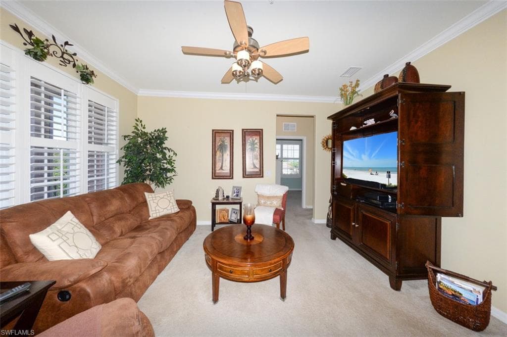 Spacious Great Room features 9'4" ceilings, Crown Molding, Plantation shutters, French door to Lanai and open to the Breakfast bar and Kitchen. Shows hallway leading to 2 guest bedrooms and a full bath.