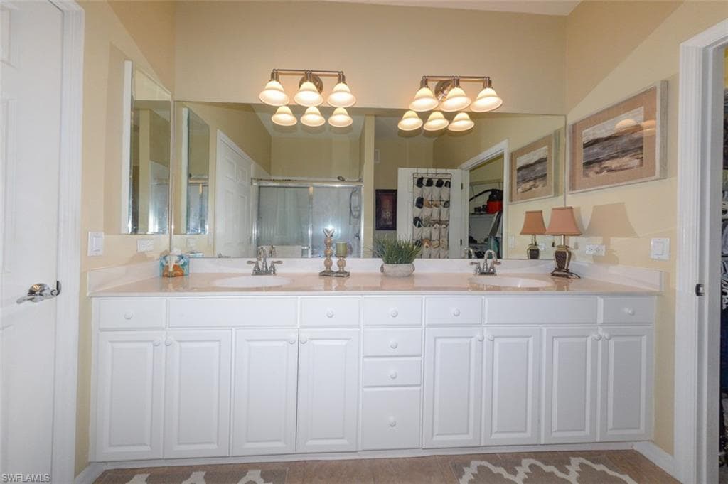 Primary suite bathroom with double sink vanity, upgraded lighting, Walk-in shower, tiled floor and large walk-in closet.