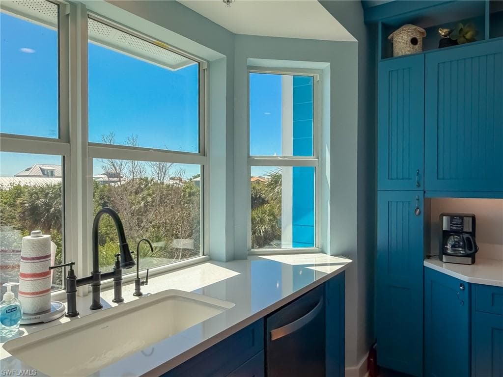 Kitchen with stainless steel dishwasher, light countertops, blue cabinets, and a sink