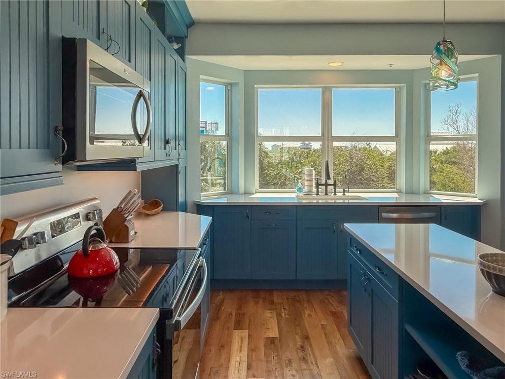 Kitchen with a sink, light countertops, blue cabinets, and stainless steel appliances