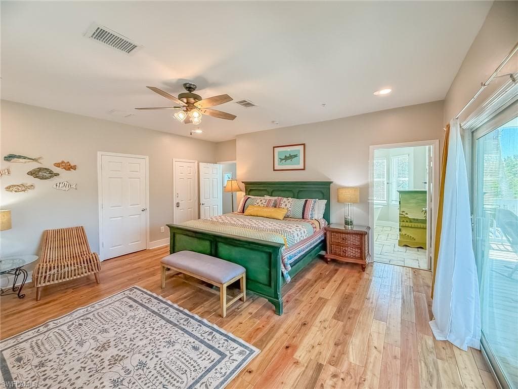 Bedroom featuring visible vents, connected bathroom, light wood-style floors, baseboards, and ceiling fan